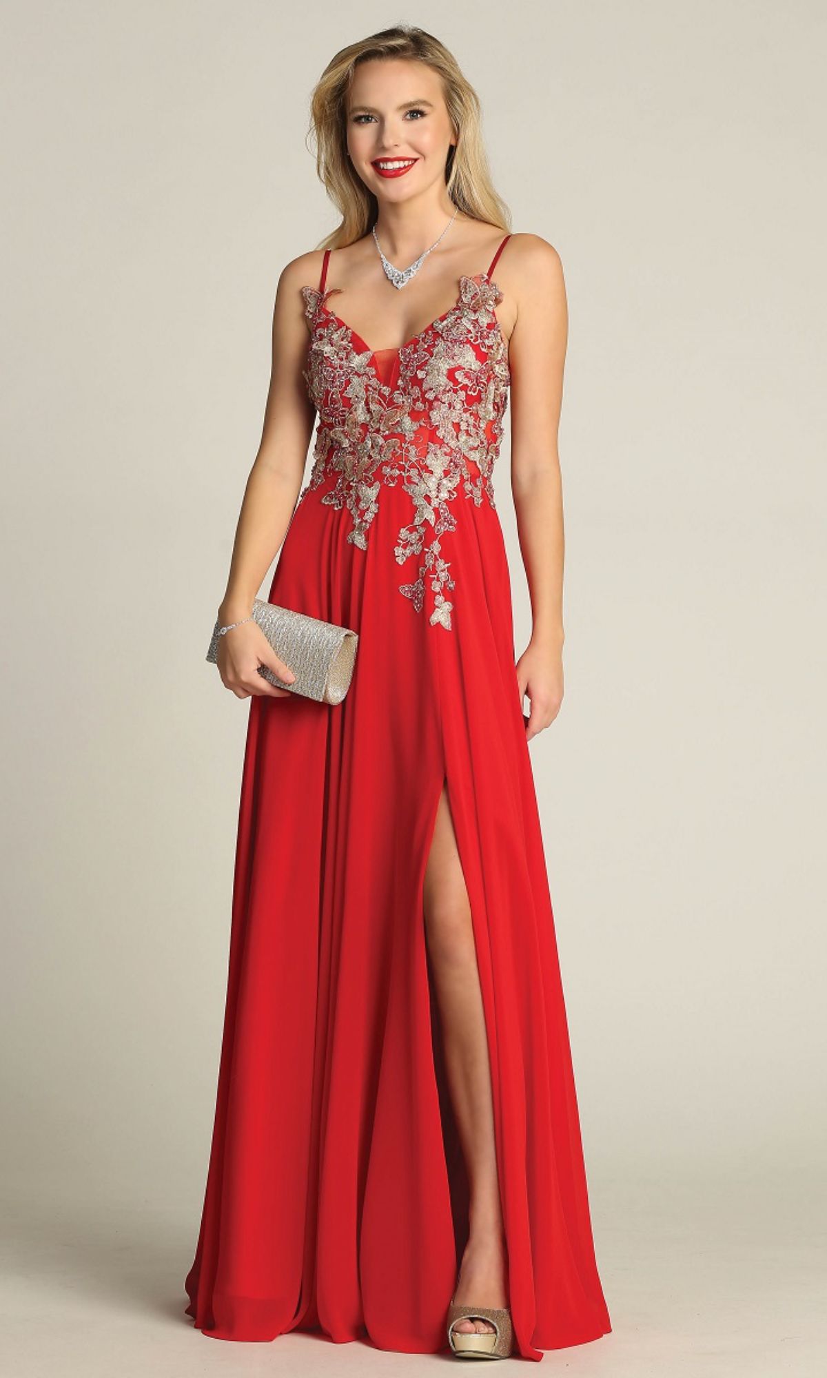Wearing the Lace-Up Open-Back Long Prom Dress: Chicas C5124, a woman stands against a plain background with a silver clutch, matching heels, and necklace, highlighting the dress’s elegant style.